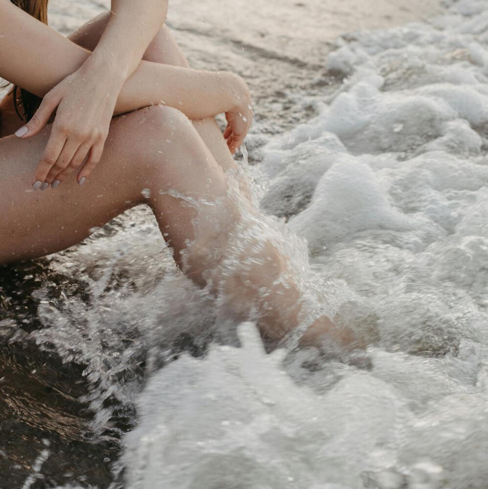 Waves crashing at the feet of a girl.